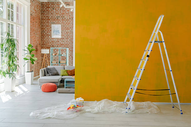 DIY interior painting project with a vibrant mustard yellow wall, white trim, and light wood flooring by a house painter in Dublin, OH.